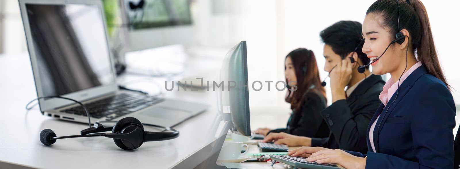 Business people wearing headset working in office in widen view to support remote customer or colleague. Call center, telemarketing, customer support agent provide service on telephone video call.