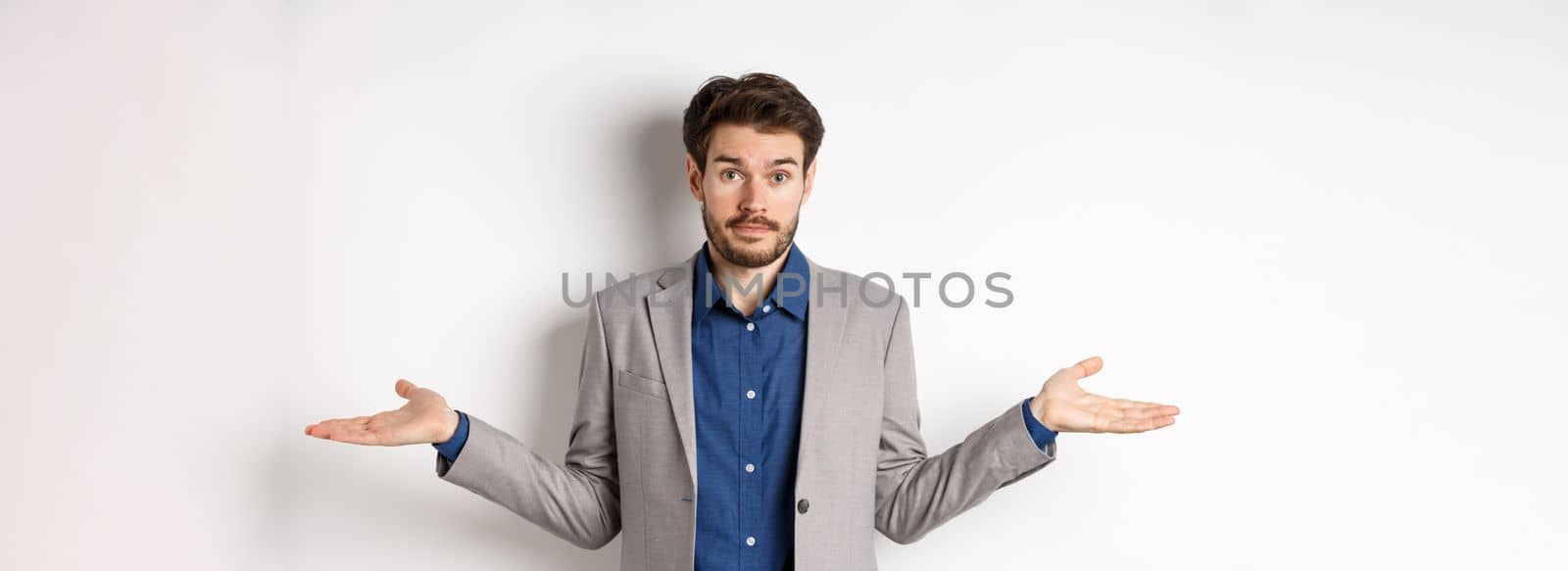 Dont know. Confused businessman spread hands sideways and look clueless, cant help, have no idea, standing on white background in suit.