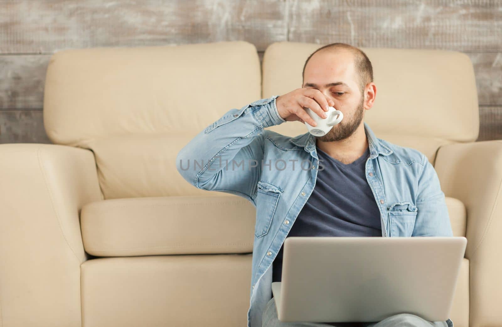 Freelancer drinking coffee while working on laptop from home.