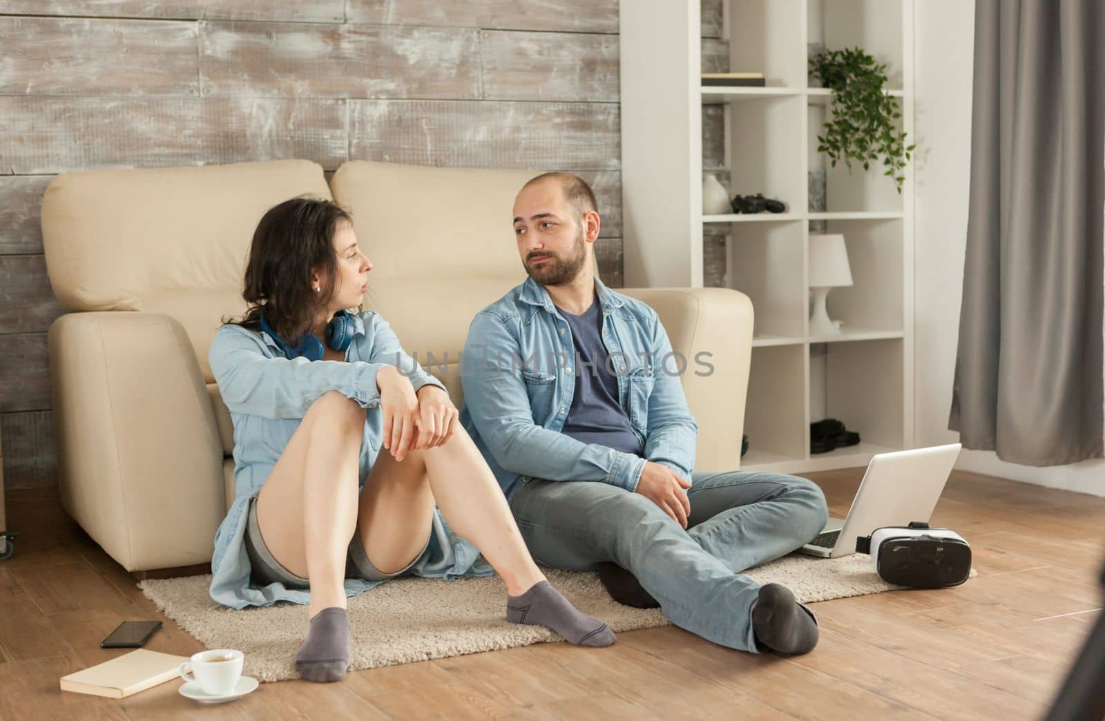 Couple looking at each other sitting down living room carpet.