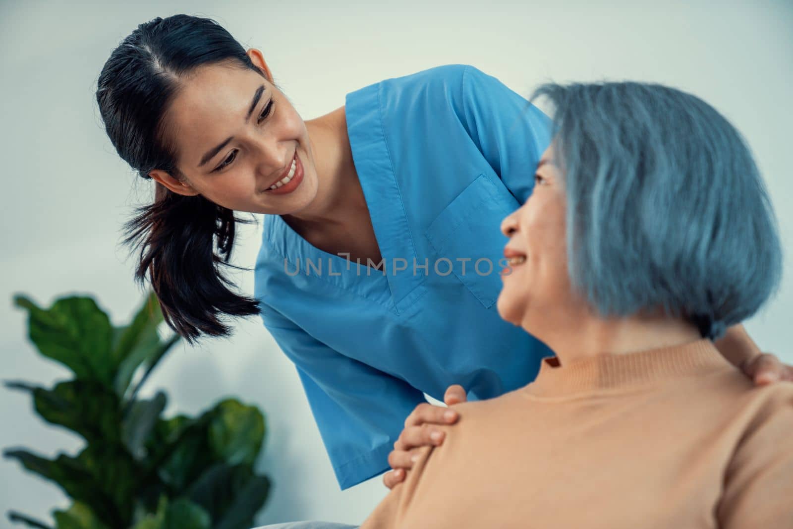 A caregiver rest her hands on the shoulders of a contented senior patient. by biancoblue