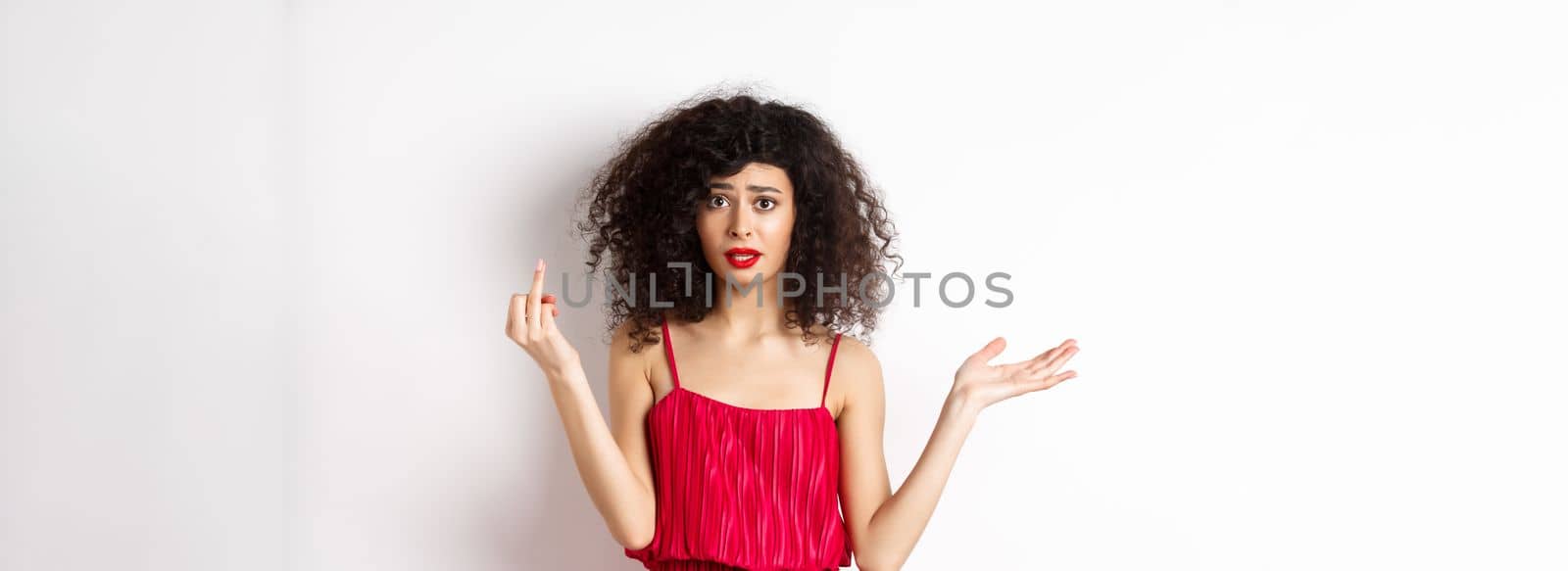 Annoyed caucasian woman in red dress, showing finger without wedding ring, arguing about marriage, standing pissed-off on white background by Benzoix