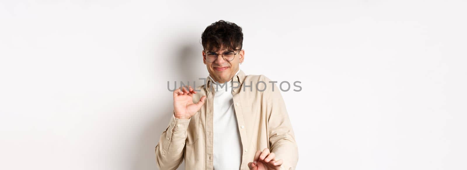 Disgusted guy grimacing and jumping away from something nasty, stare with aversion and dislike, rejecting bad offer, standing on white background by Benzoix