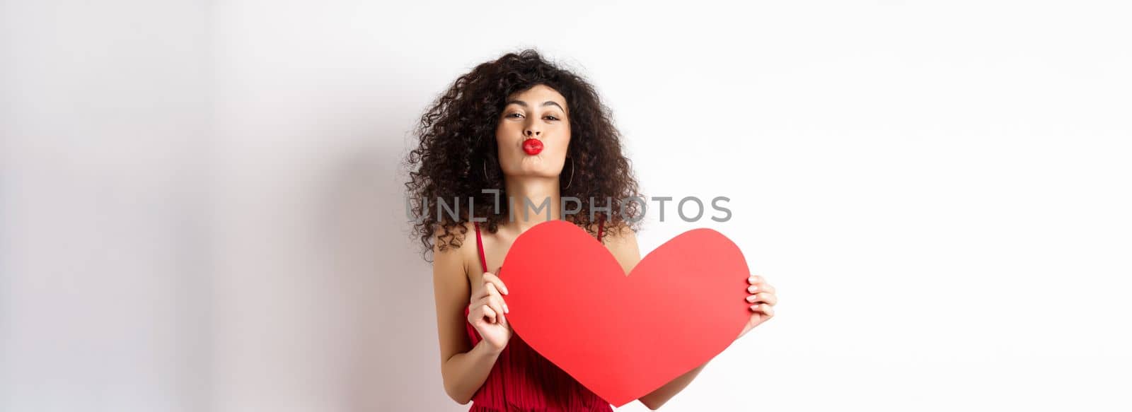 Romantic woman in dress showing big red heart, pucker lips for kiss and express love, express sympathy, white background by Benzoix