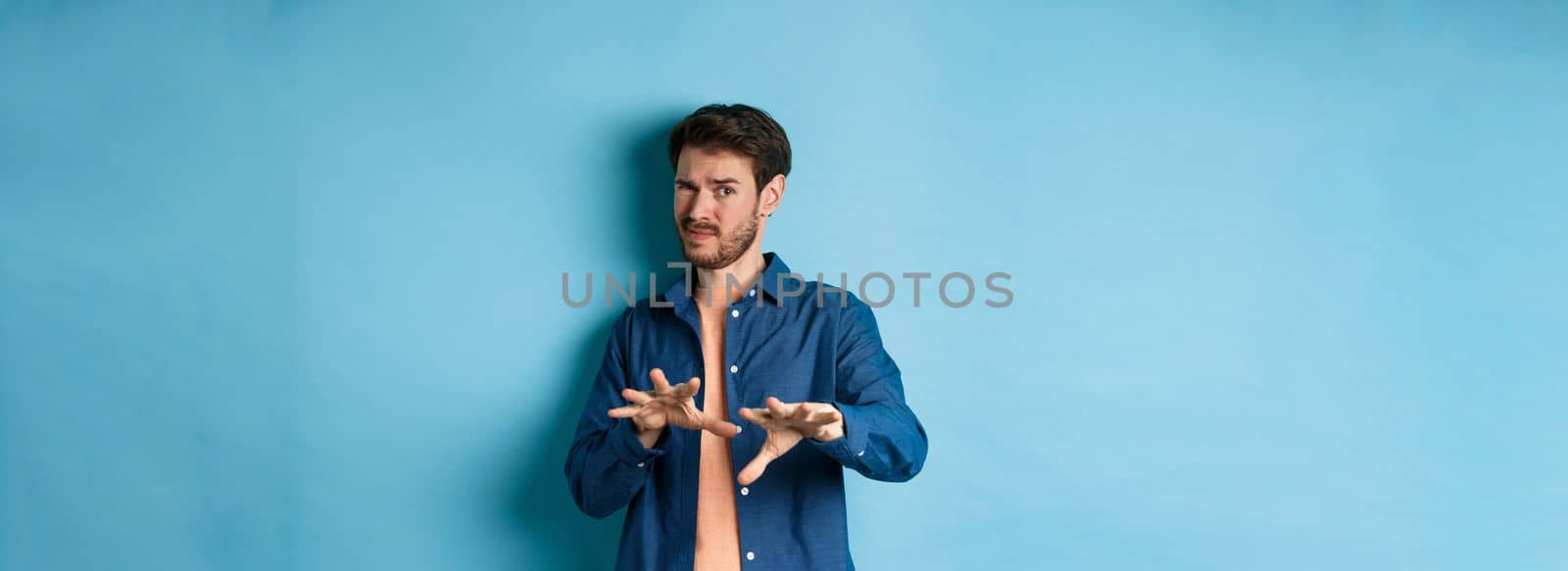 Guy cringe from something awful and nasty, refusing from bad ofer, looking disgusted, standing on blue background. Copy space