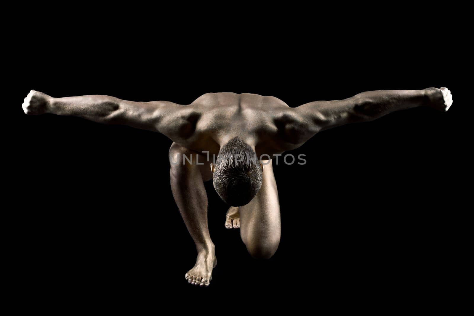 Strong nude man with gold skin make up posing in dark