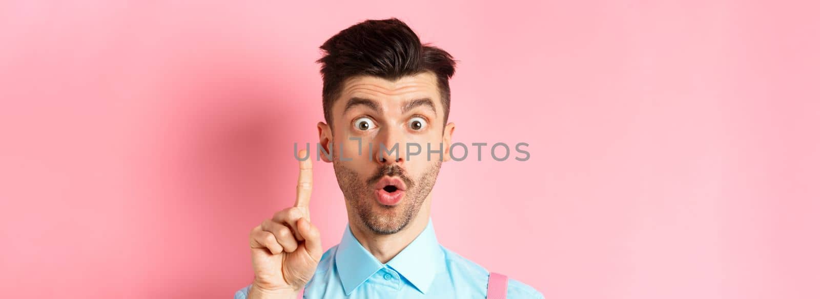 Close-up of excited guy pitching an idea, raising finger and saying suggestion, have a plan, standing on pink background by Benzoix