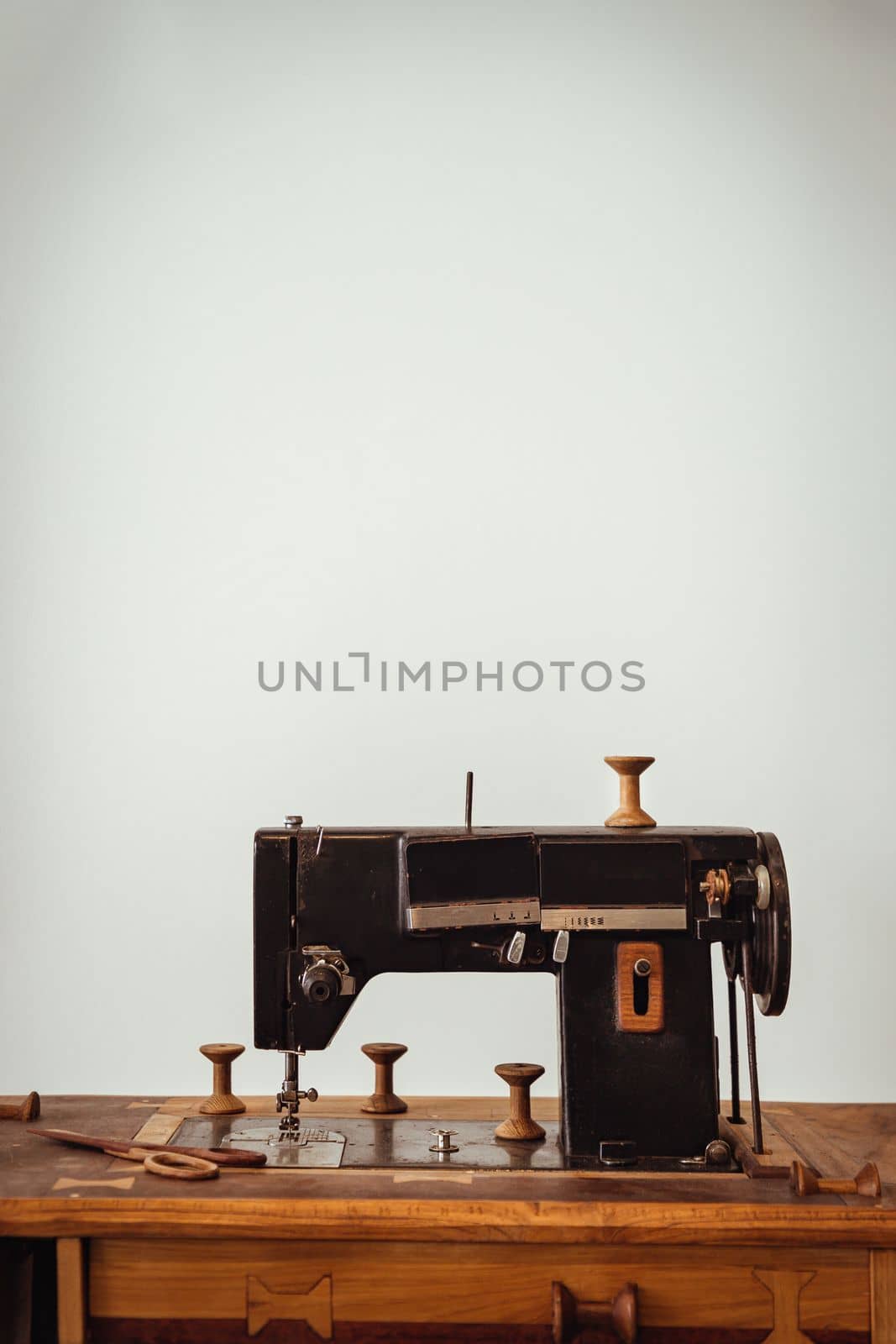 Old vintage sewing machine on wooden table on white wall background. Copy space, Selective focus.