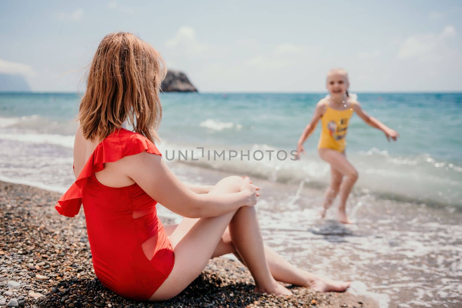 Happy loving family mother and daughter having fun together on the beach. Mum playing with her kid in holiday vacation next to the ocean - Family lifestyle and love concept by panophotograph