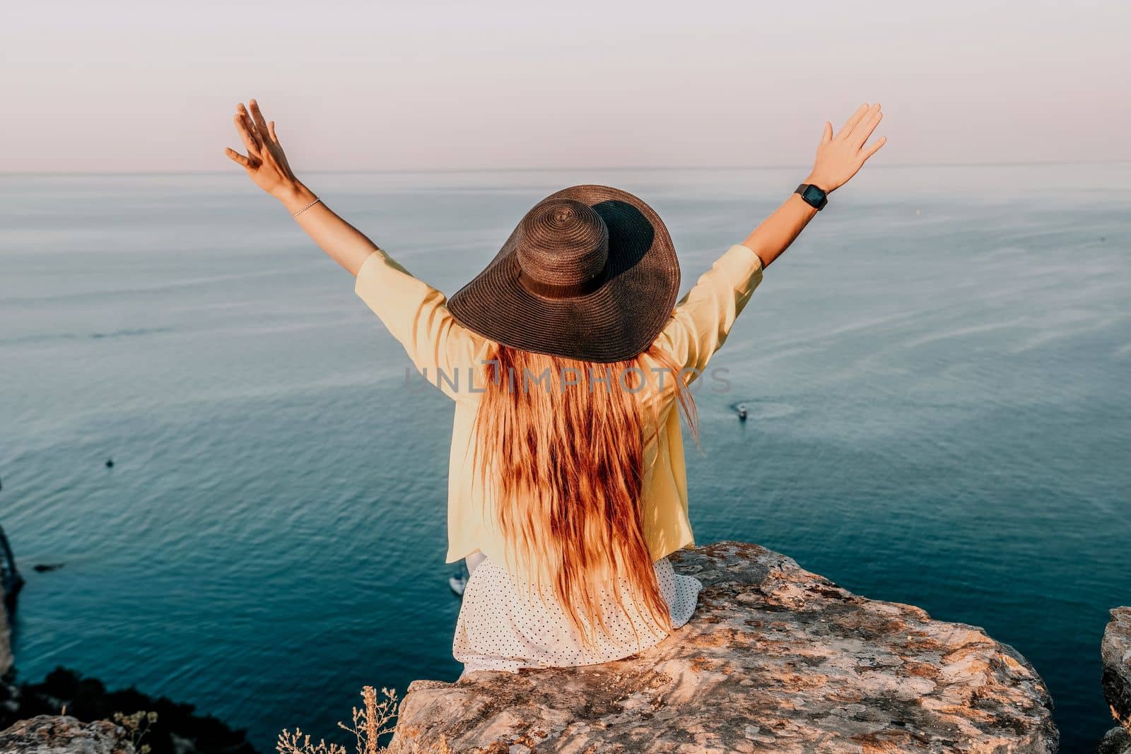 Portrait of happy young woman wearing summer black hat with large brim at beach on sunset. Closeup face of attractive girl with black straw hat. Happy young woman smiling and looking at camera at sea