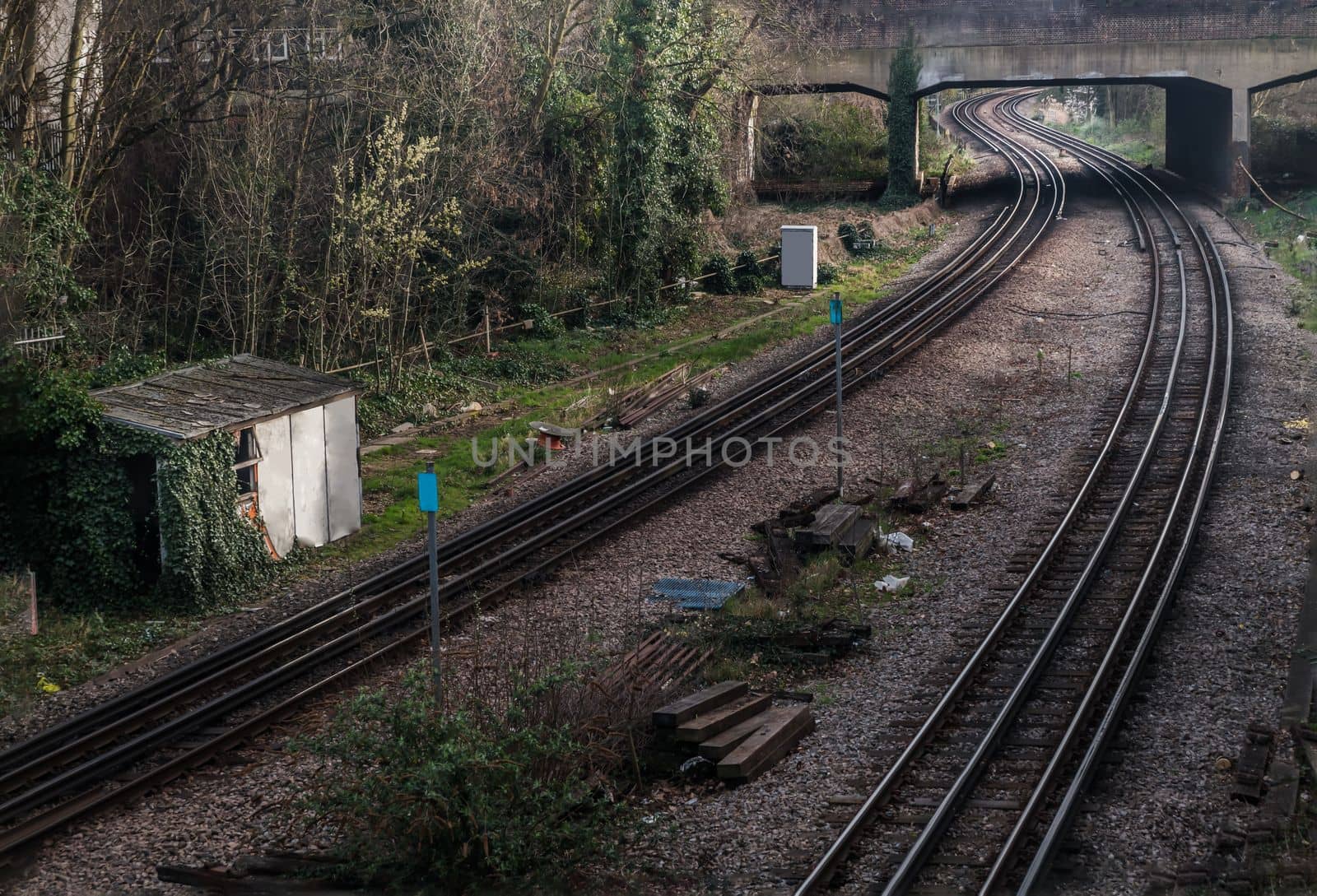 Two old railway tracks stretching into passing under the bridge.  by tosirikul