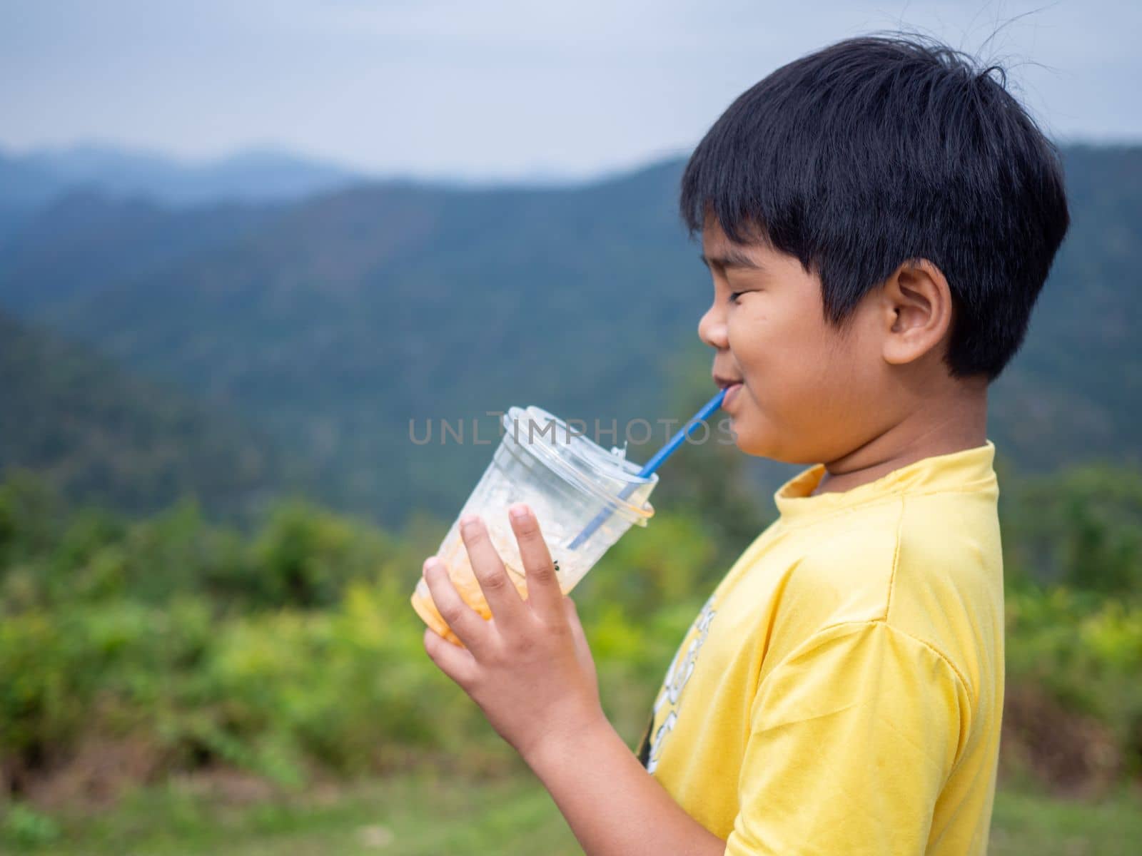 boy sucking a drink from a glass with a valley background