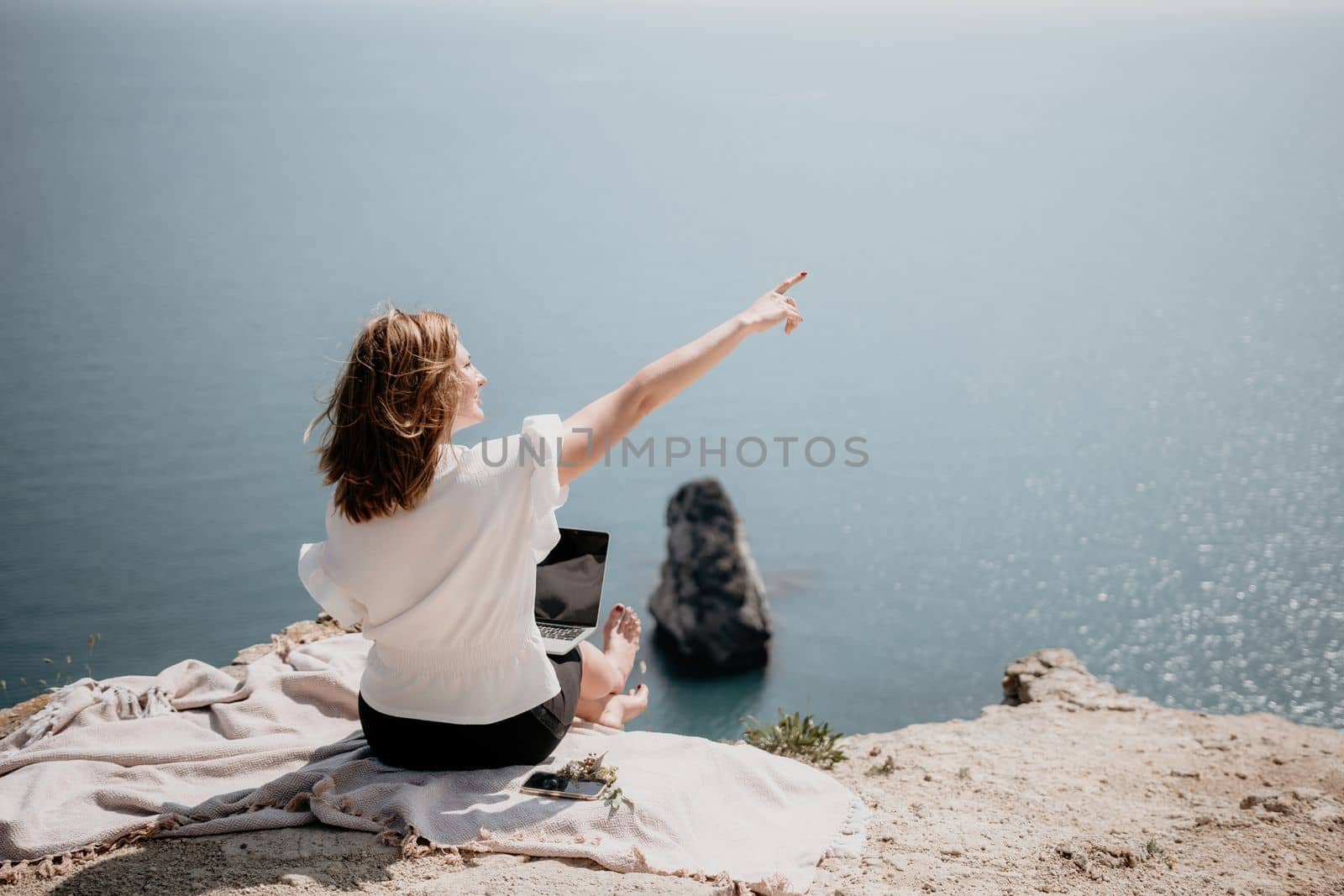 Woman sea laptop. Successful business woman working on laptop by the sea. Pretty lady typing on computer at summer day outdoors. Freelance, digital nomad, travel and holidays concept. by panophotograph