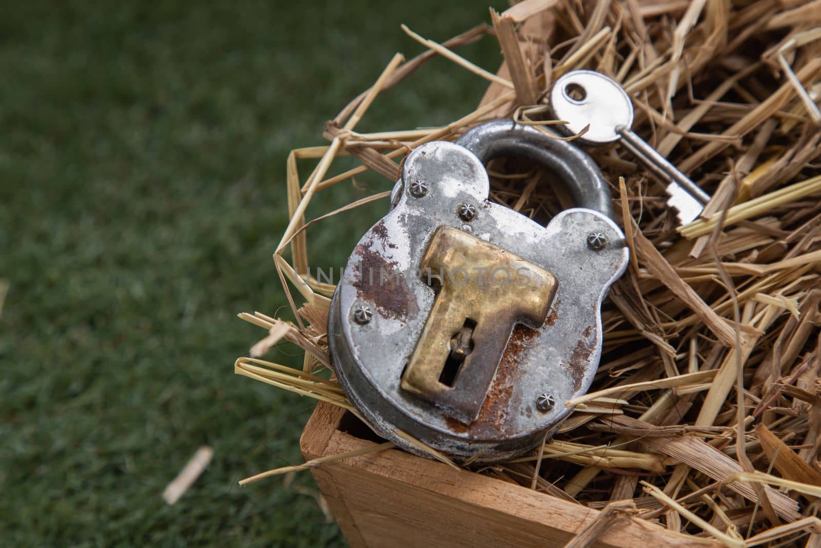 Old vintage iron padlock and key on straw background in wooden box. Copy spce, Selective focus.