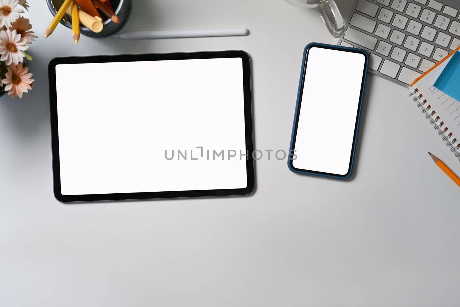 Digital tablet, smart phone and stationery on white table.