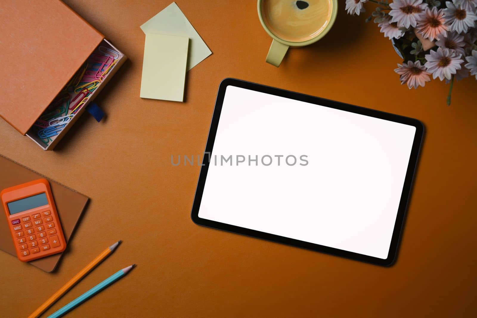 Top view digital tablet, calculator and coffee cup on orange leather.