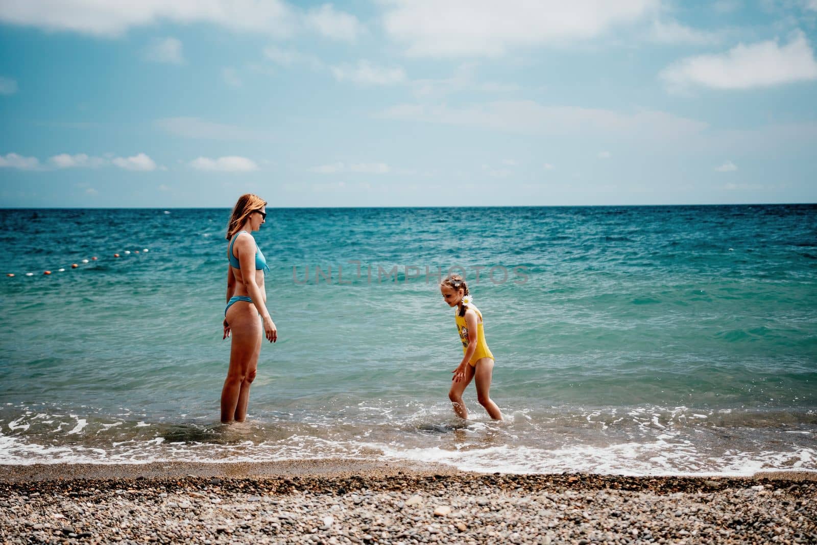 Happy loving family mother and daughter having fun together on the beach. Mum playing with her kid in holiday vacation next to the ocean - Family lifestyle and love concept.