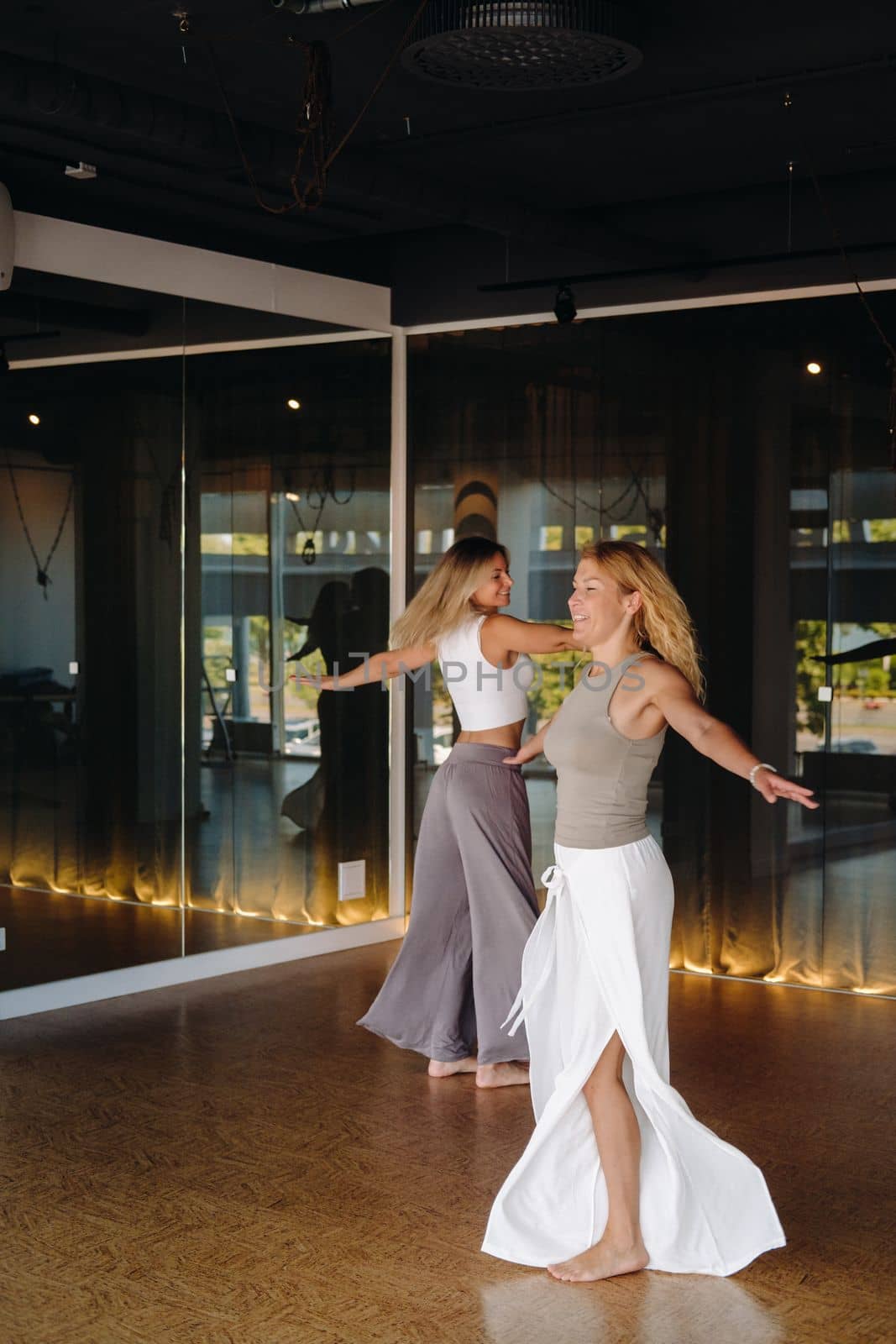 Two women in sportswear are doing dance yoga in the gym by Lobachad