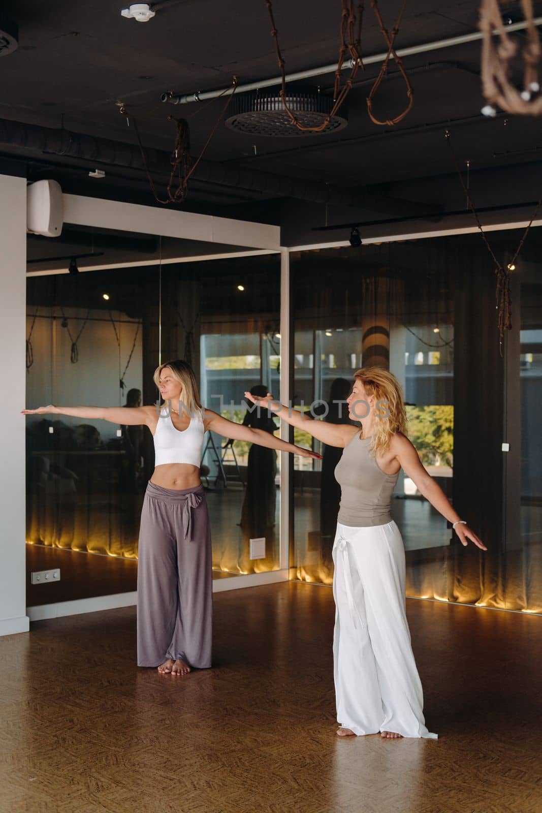 Two women in sportswear are doing dance yoga in the gym.