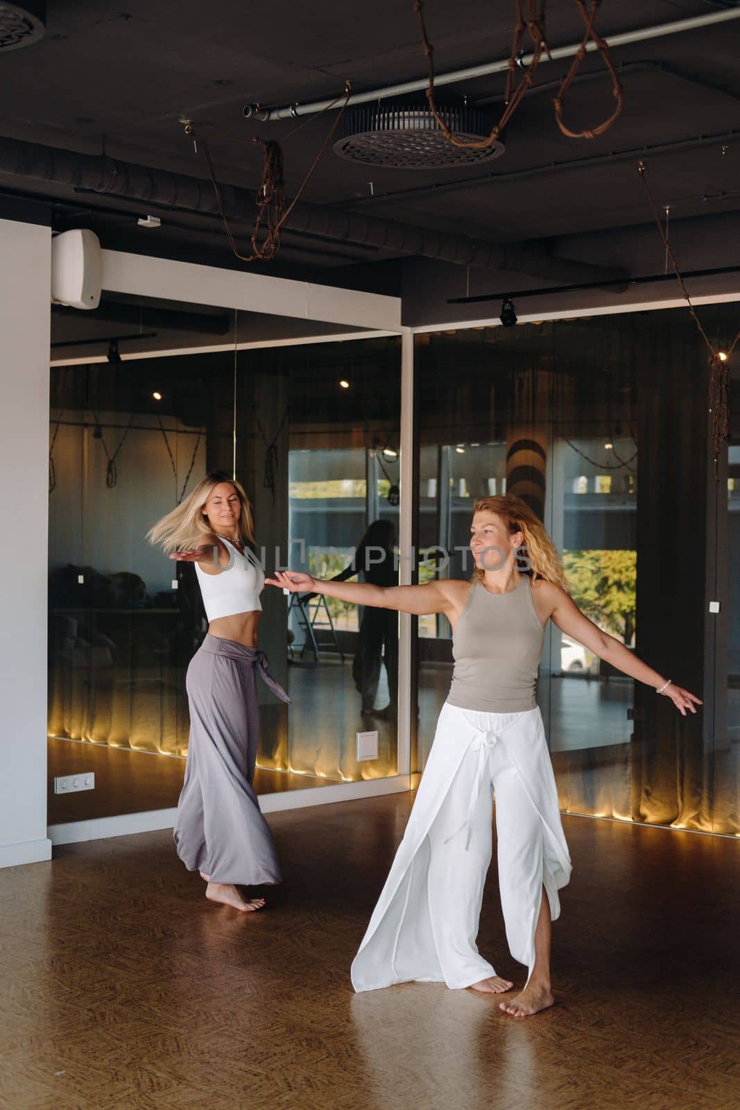 Two women in sportswear are doing dance yoga in the gym by Lobachad