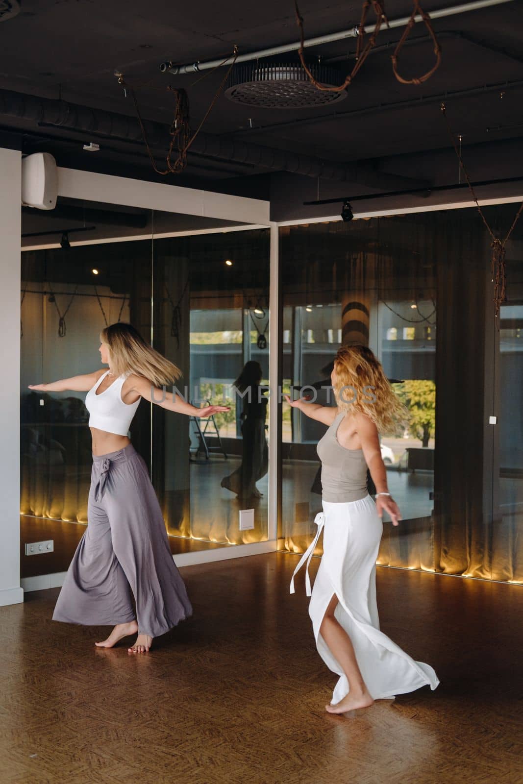 Two women in sportswear are doing dance yoga in the gym.