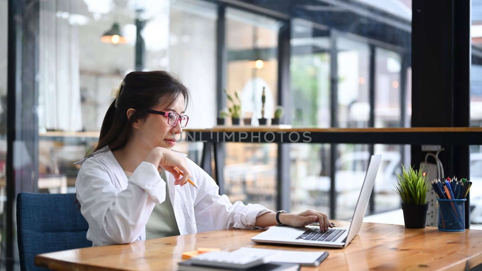 Female entrepreneur working with laptop computer at modern workplace. by prathanchorruangsak