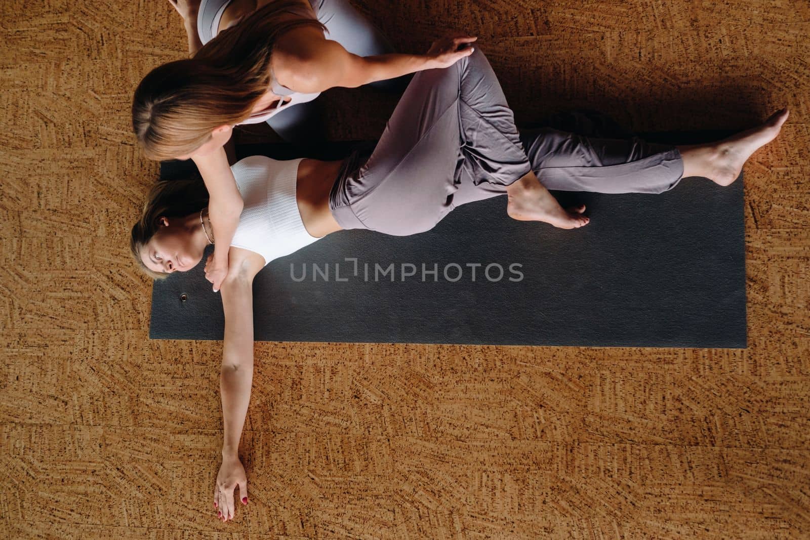 Yoga exercises. A personal trainer teaches a woman yoga classes in the gym by Lobachad