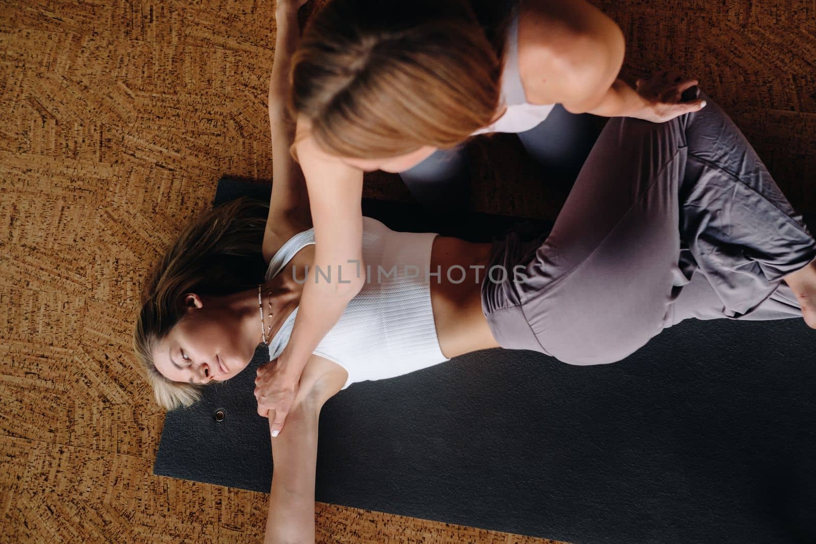 Yoga exercises. A personal trainer teaches a woman yoga classes in the gym by Lobachad