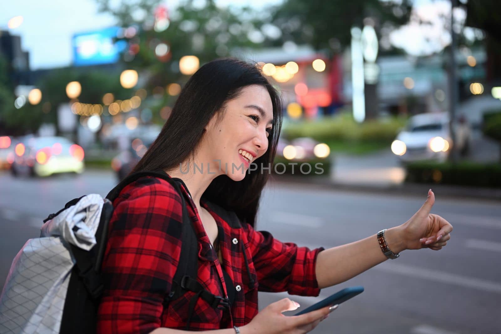 Smiling Asian woman using application of taxi service app on smart phone.