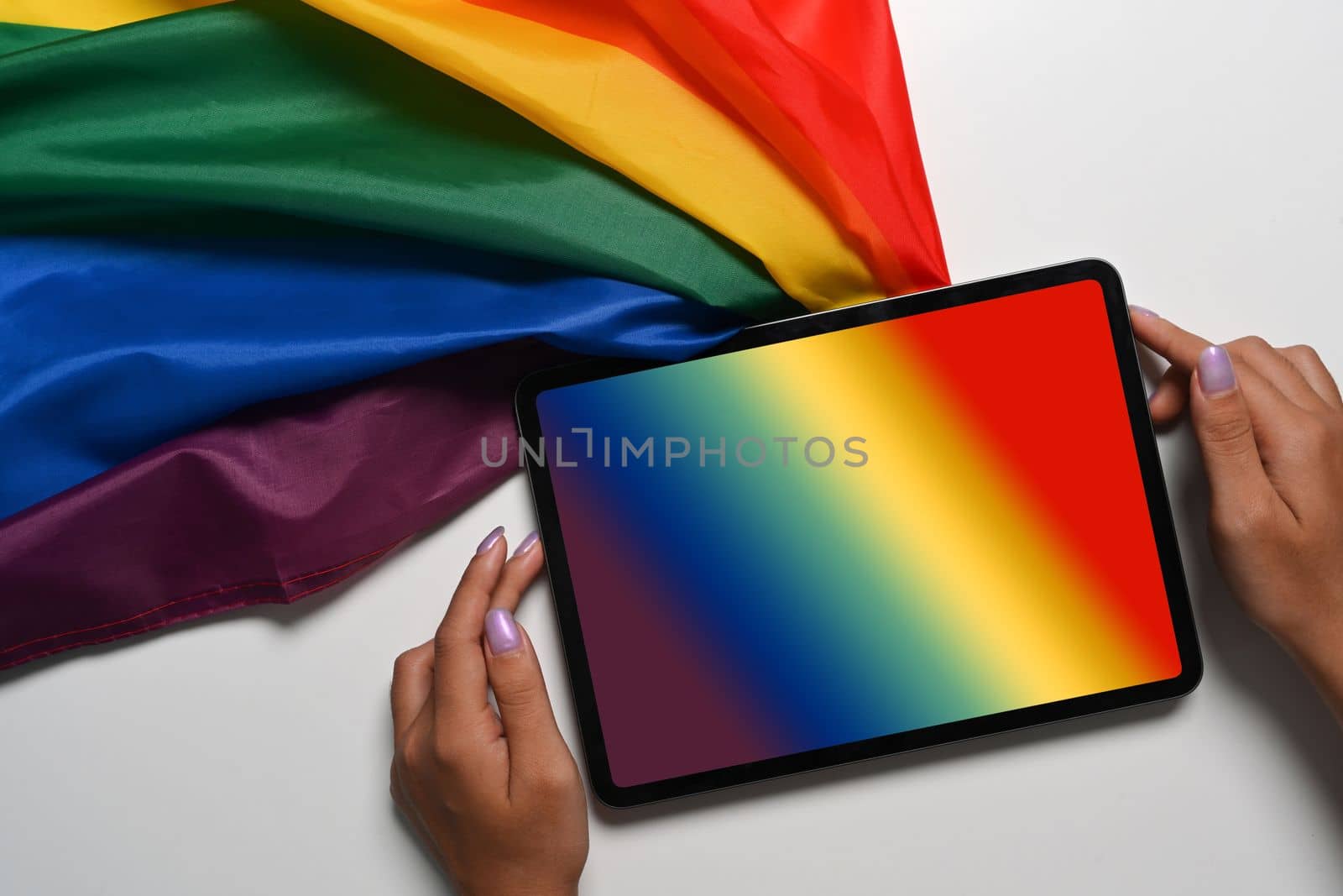Above view female holding digital tablet with rainbow flag on white background. by prathanchorruangsak