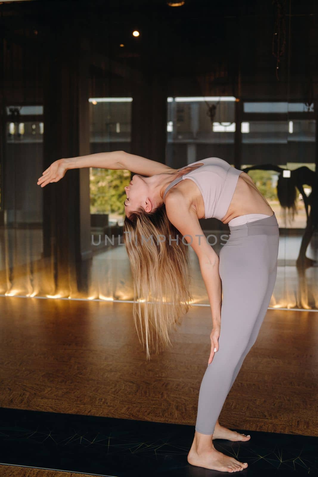 The girl does yoga. A woman in sports clothes does yoga exercises in the gym.