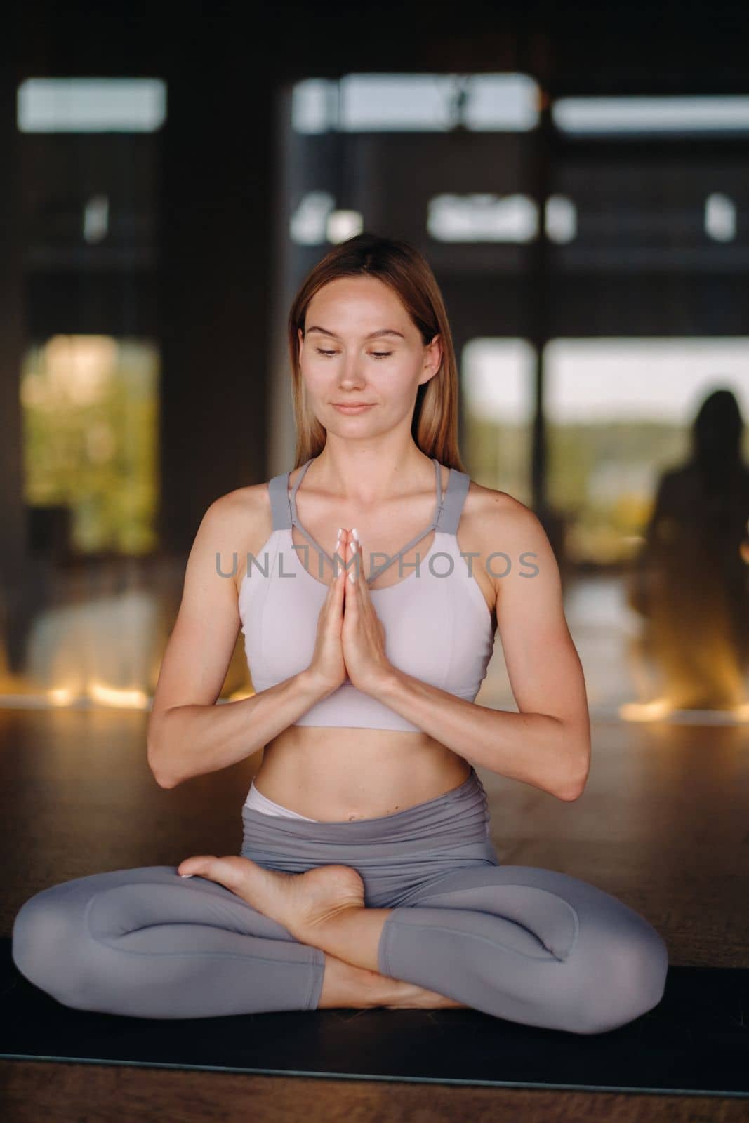 The girl does yoga. A woman in sports clothes does yoga exercises in the gym.