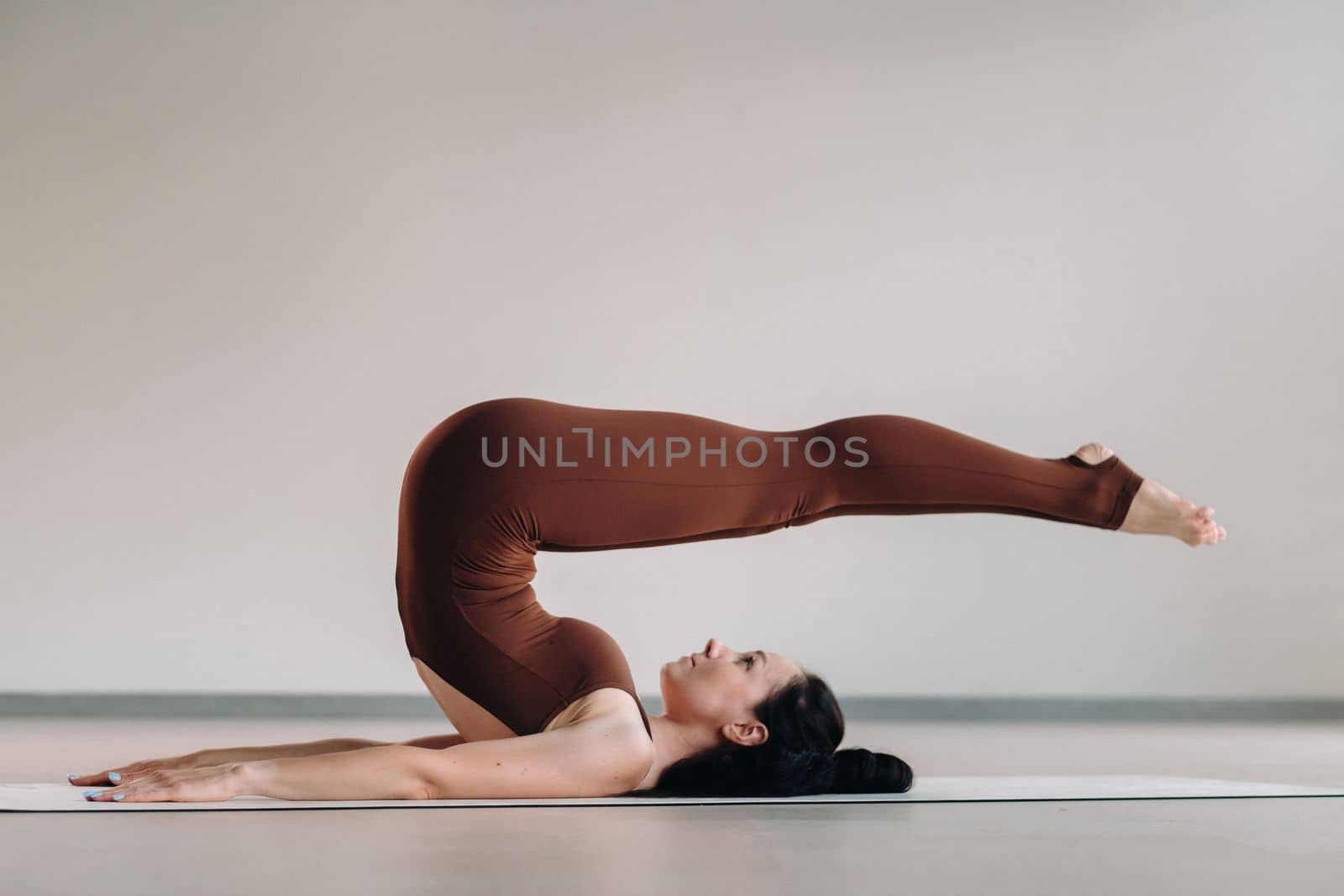 a woman in a brown suit does yoga in a fitness room . Healthy lifestyle, fitness, training, self-care.