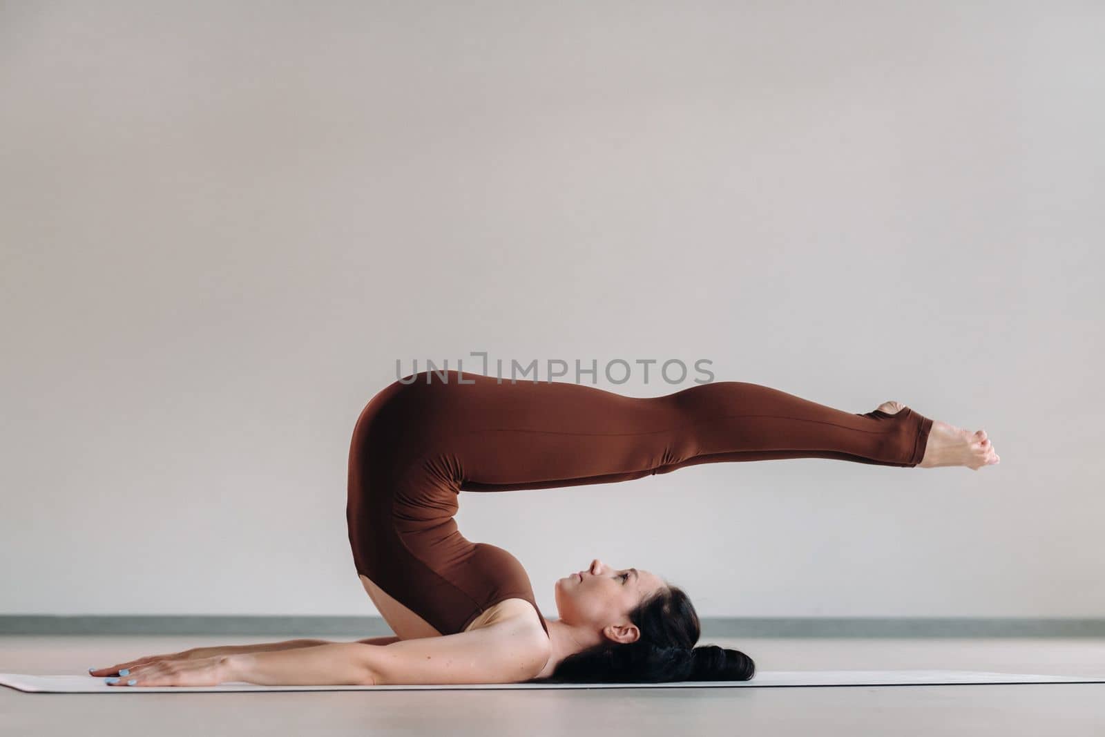 a woman in a brown suit does yoga in a fitness room . Healthy lifestyle, fitness, training, self-care.