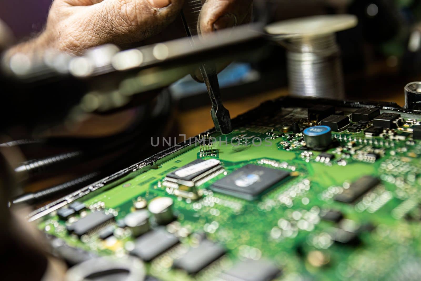 Car Ecu Detail with visible components with hand that repair it. Car ecu repair detail. Electronic board repair