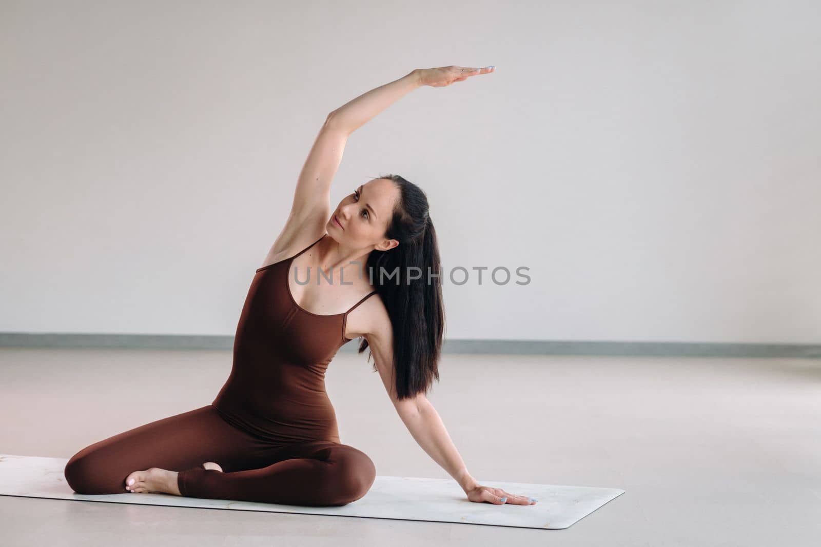 a woman in a brown suit does yoga in a fitness room . Healthy lifestyle, fitness, training, self-care.