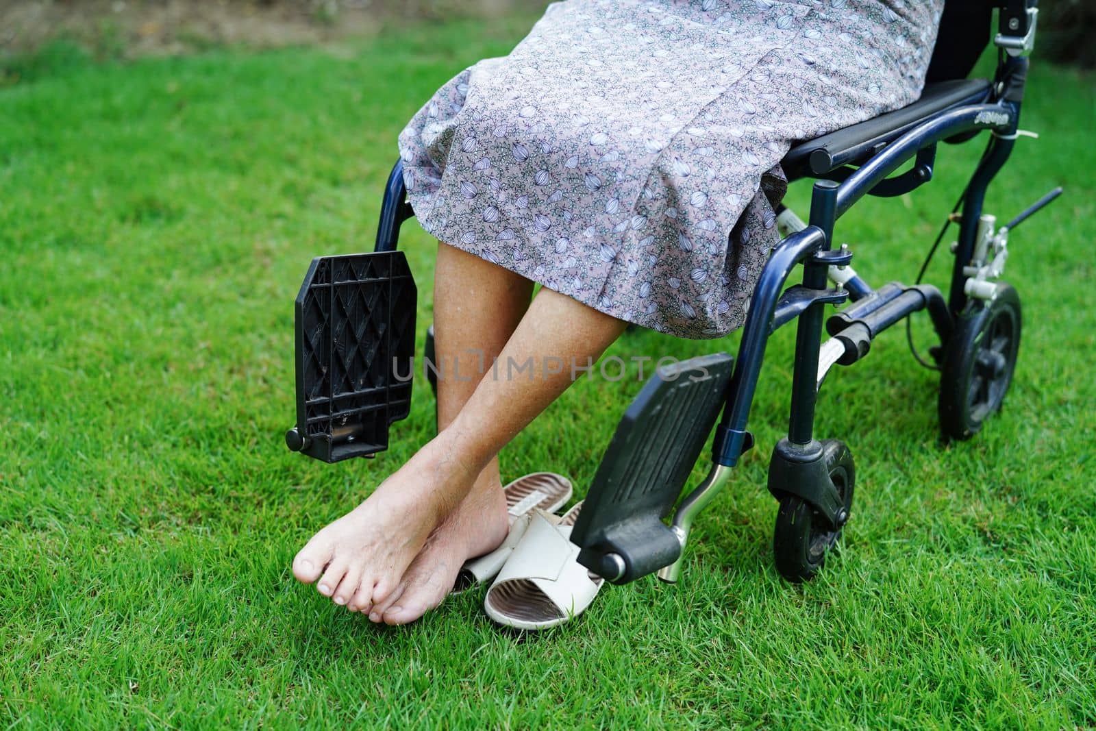 Asian elderly woman disability patient sitting on wheelchair in park, medical concept.