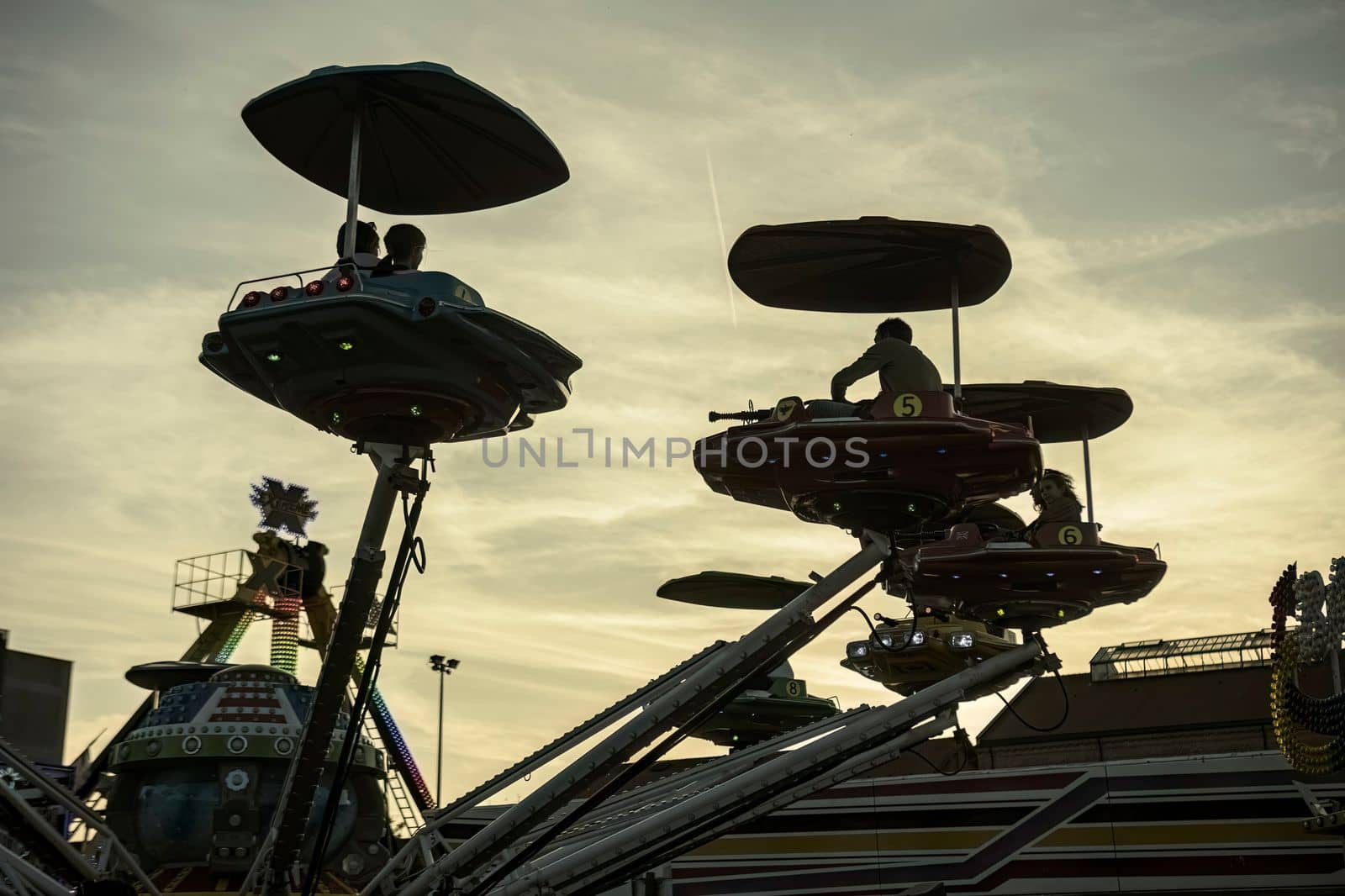 Rovigo, Italy 25 October 2022: Carousel fairground plane at sunset silhouette