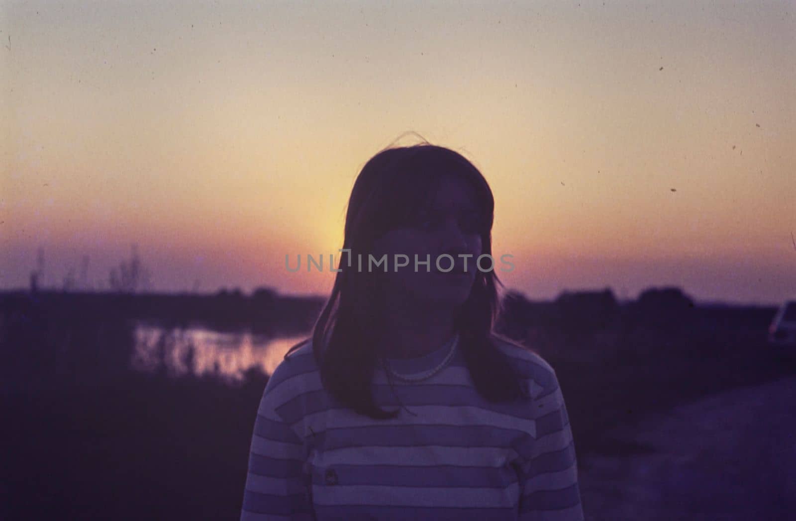 Rovigo, Italy october 1976: Girl silhouette sunset countryside scene in 70s