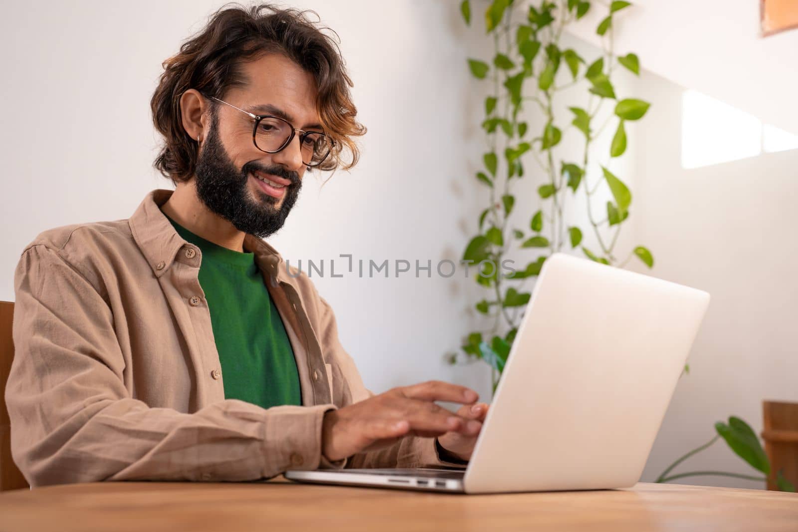 Cheerful male writer working on a novel on his laptop at home. Man imagining and thinking stories to write a story book. Real people. High quality photo