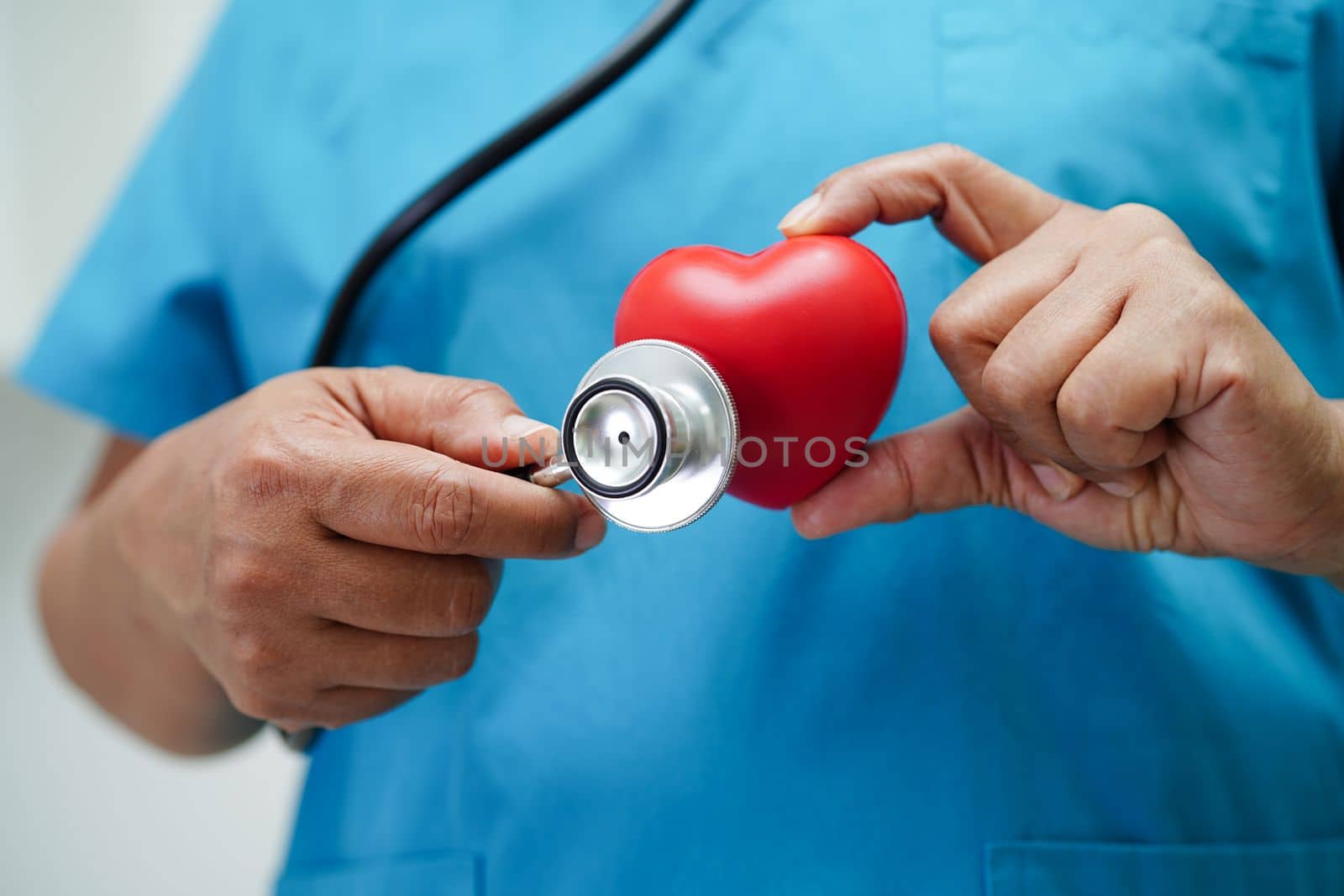 Asian woman doctor holding red heart for health in hospital.