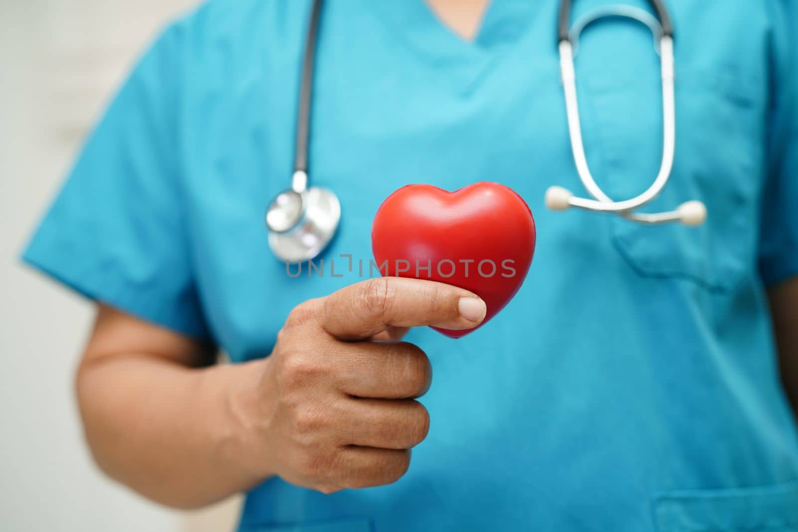 Asian woman doctor holding red heart for health in hospital.