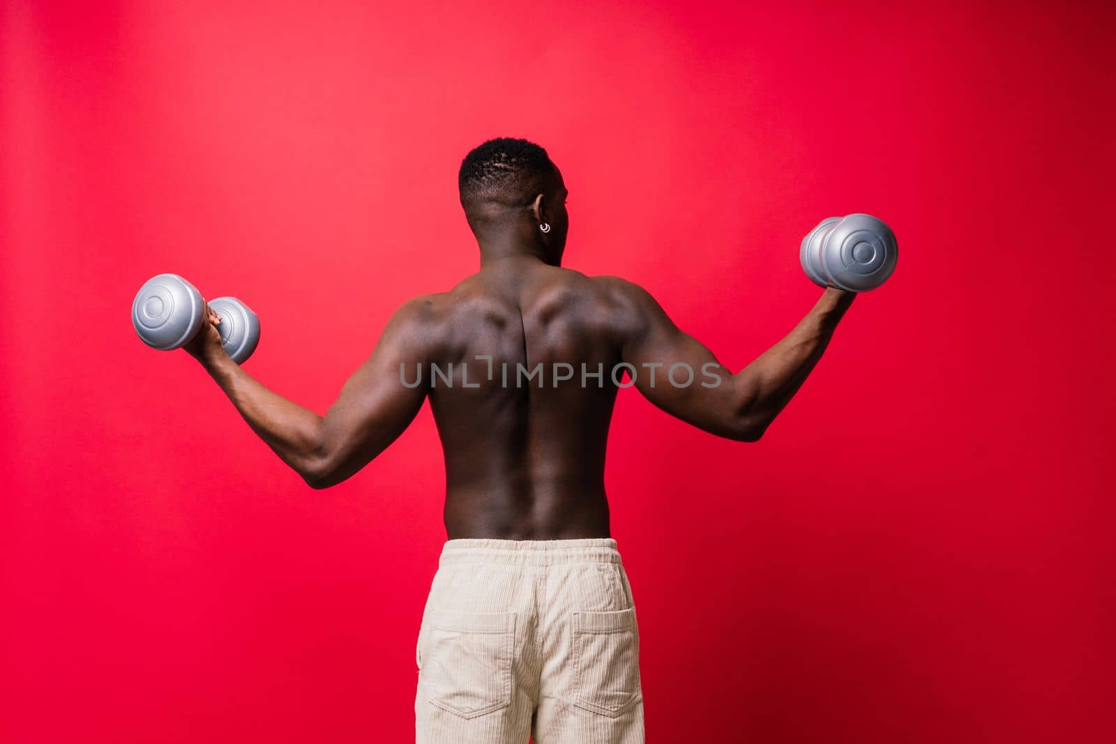 Portrait of a happy african man with dumbbells over red background by Zelenin