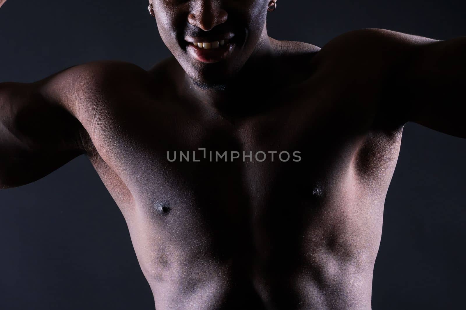 Portrait of athletic african american man topless, black background