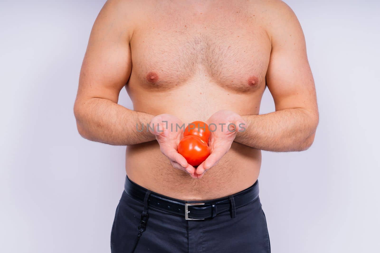 Full isolated studio picture from a young naked man with underwear and tomatoes