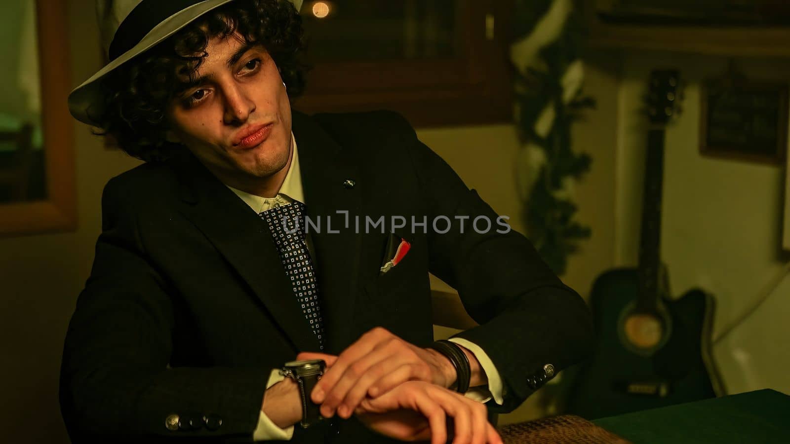 A man sitting in front of a briefcase on the table, checking the time on his wristwatch. He nods in affirmation, giving the impression that he is ready to close a deal.