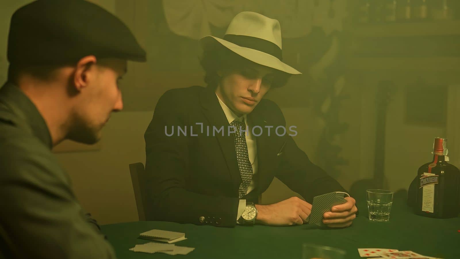 A poker player sits at a dimly lit table, staring down at their cards with a defeated expression. Disappointment and defeat associated with gambling.