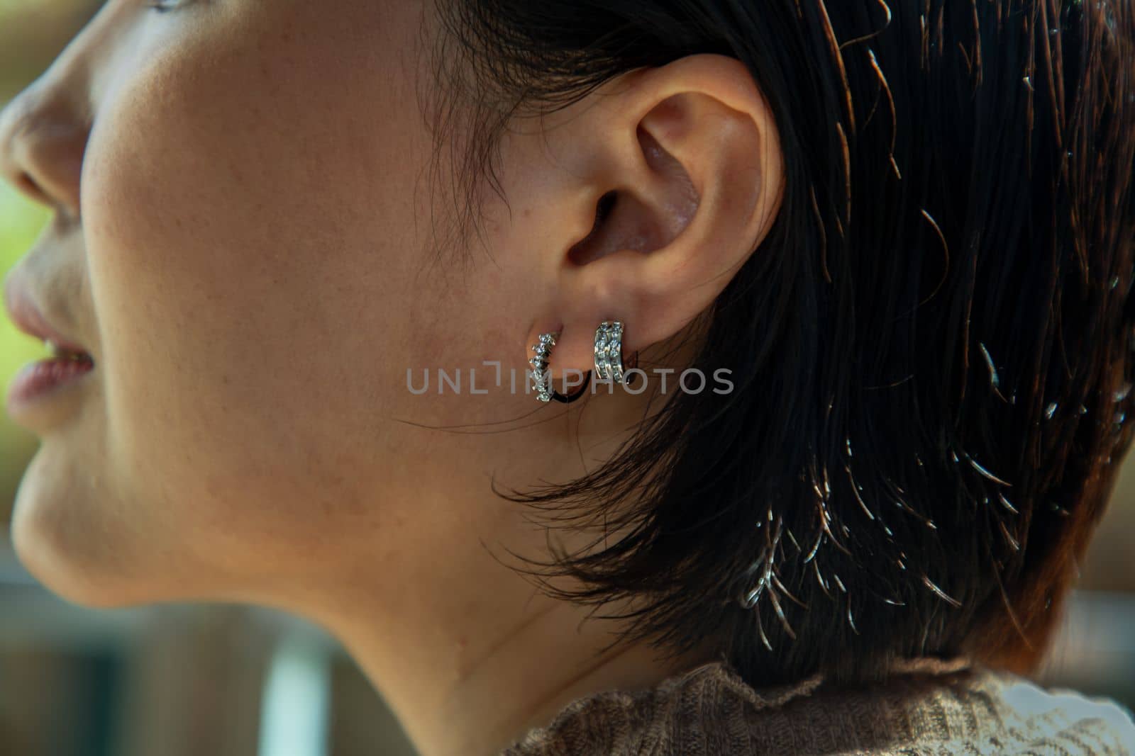 Detail of young woman wearing beautiful silver earring. Women accessories. Selective focus.