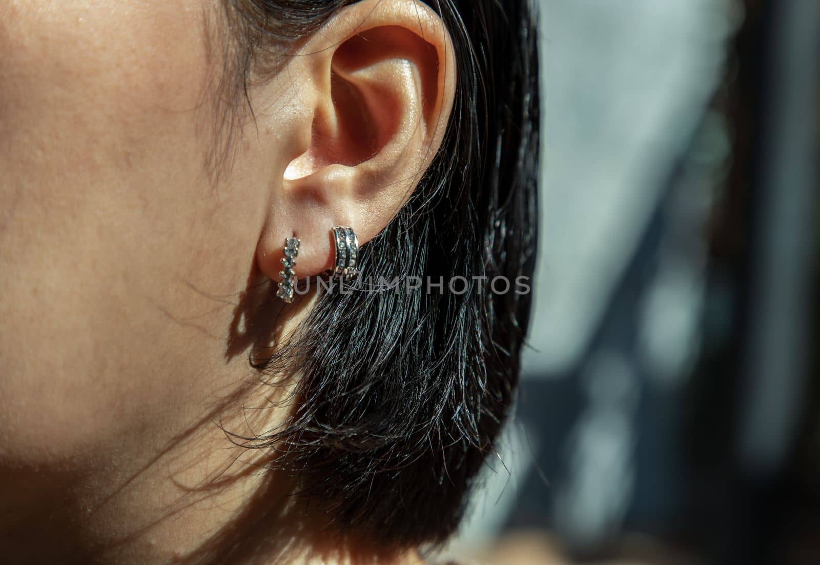 Detail of young woman wearing beautiful silver earring. Women accessories. Selective focus.