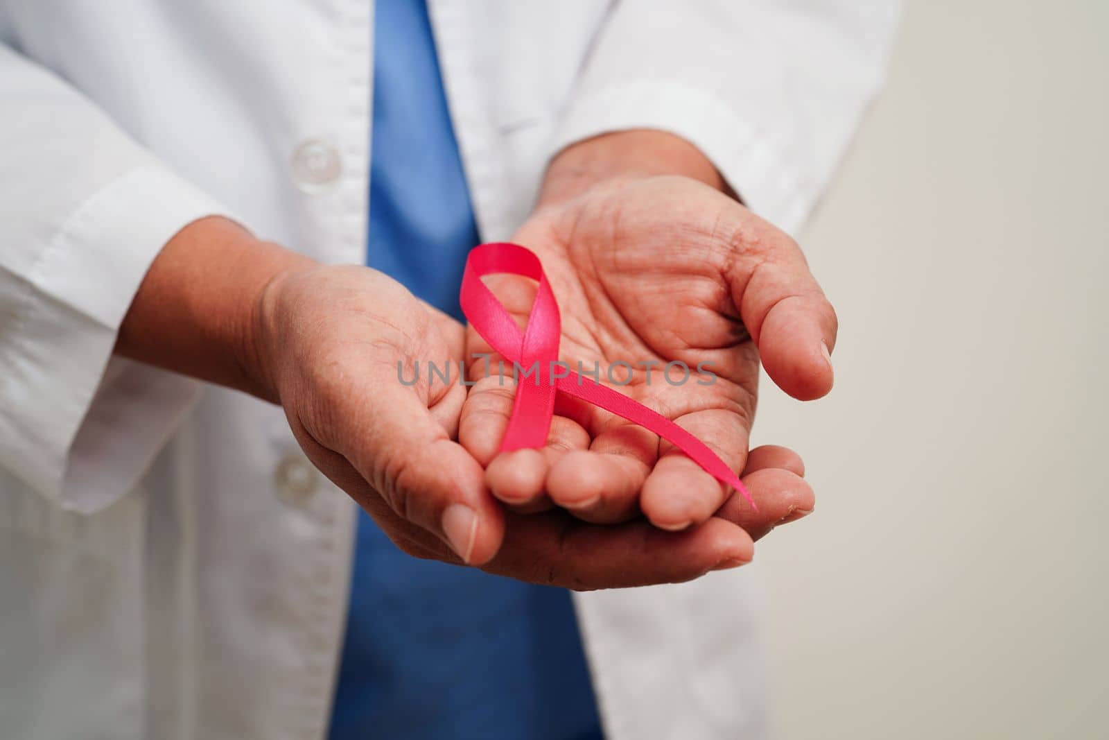 Asian woman doctor with pink ribbon, World Breast Cancer Day at October.